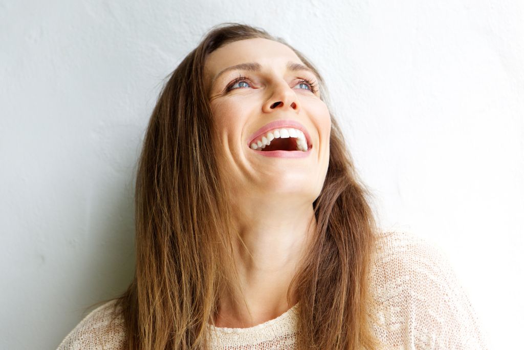 Portrait photography of a woman with brown hair, looking up and laughing