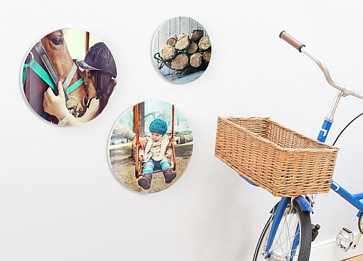 Circle-shaped wallart hung up on a wall next to a bicycle, showing a kid, a horse and wood
