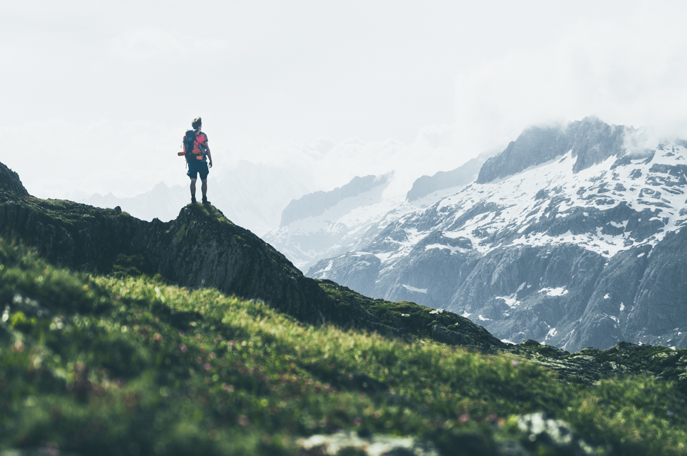 Man in the Bernese alps on Sidelhorn mountain, looking at a snow-covered mountain range