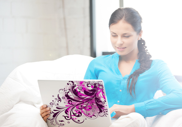 Woman sitting on the sofa holding a laptop with laptop skin with purple pattern as personalized photo gift idea
