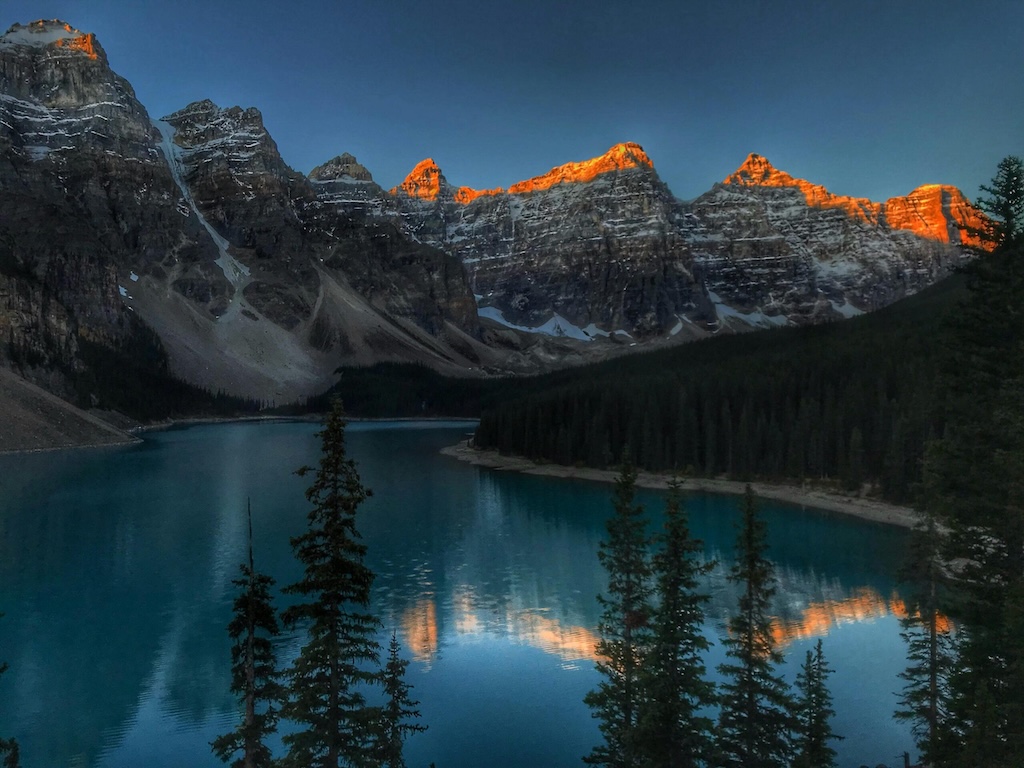 Landscape photography of a mountain lake during sunrise with illuminated mountain peaks