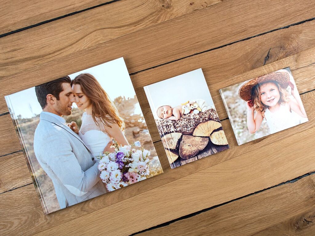 Photo books showing a wedding couple, a baby sleeping on wood and a girl with hat as unique photo gift ideas