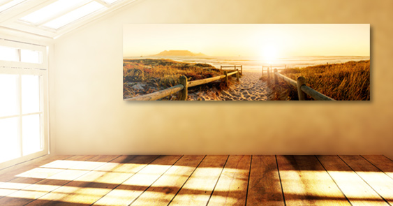 Panoramic image showing a beach with dunes, hung up in a sun-drenched living room with wooden floors