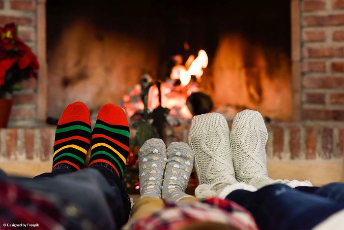 Family Christmas pictures of legs wearing colorful socks in front of a campfire.