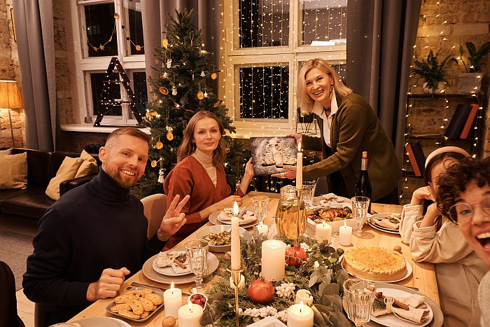 Christmas family photo of a family of five persons sitting at the decorated dining table in front of a Christmas tree.