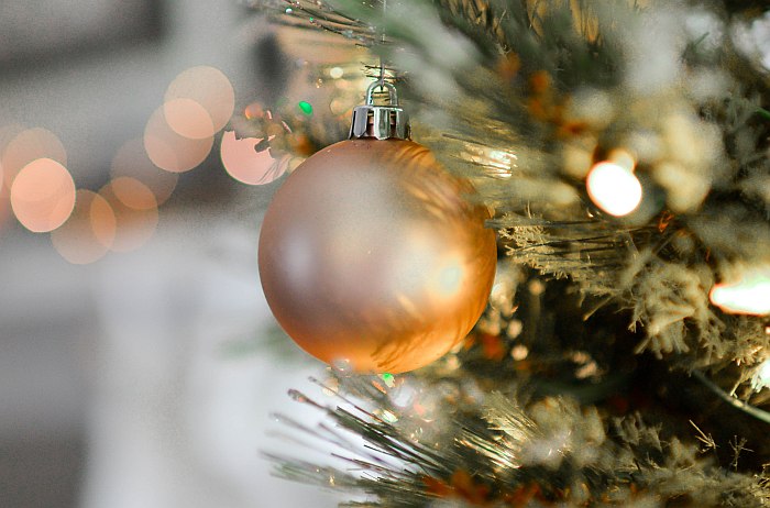 Photo of a gold Christmas bauble at a christmas tree, creating a warm and cozy atmosphere.